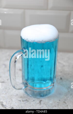 Dans un liquide bleu spumeux beer mug Banque D'Images