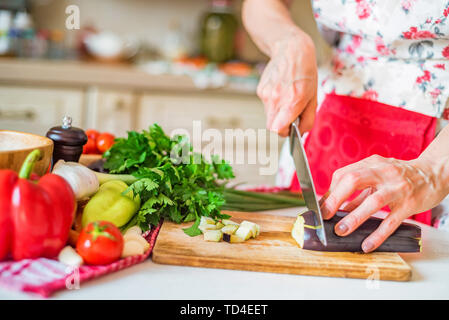 Main de femme Close up avec entaille l'aubergine sur planche de bois dans la cuisine Banque D'Images
