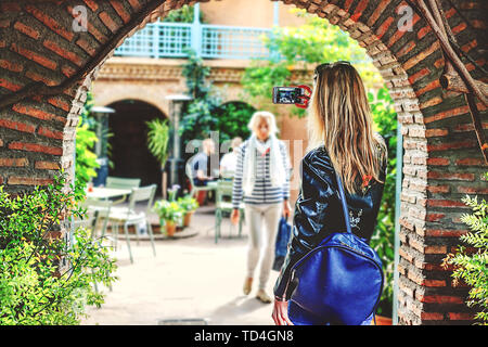 Une fille aux cheveux blonds prend des photos des sites touristiques sur le téléphone, avec son dos à la caméra. Maroc Banque D'Images