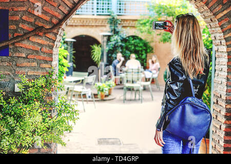 Une fille aux cheveux blonds prend des photos des sites touristiques sur le téléphone, avec son dos à la caméra. Maroc Banque D'Images