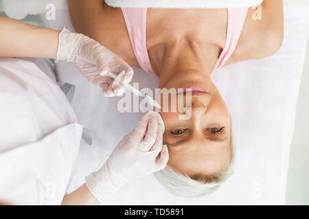 La peau lisse. Vue de dessus d'une belle femme mature une injection dans sa joue Banque D'Images