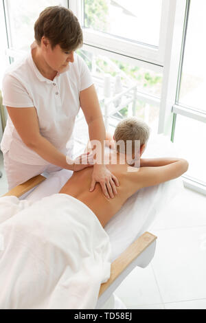 Faire le massage. Masseuse professionnelle grave en se concentrant sur son travail tout en faisant le massage pour le client Banque D'Images