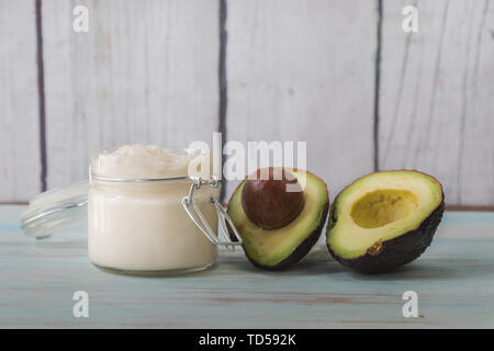 Crème visage fait maison de l'huile d'avocat. La crème fait maison dans un bol en verre fendu en deux l'avocat Banque D'Images