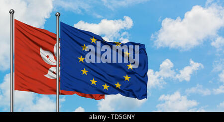 Hong Kong et de l'Union européenne drapeaux dans le vent contre ciel bleu nuageux blanc ensemble. Concept de diplomatie, de relations internationales. Banque D'Images