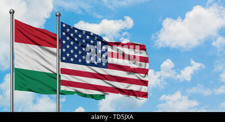 La Hongrie et de brandir le drapeau des États-Unis dans le vent contre ciel bleu nuageux blanc ensemble. Concept de diplomatie, de relations internationales. Banque D'Images