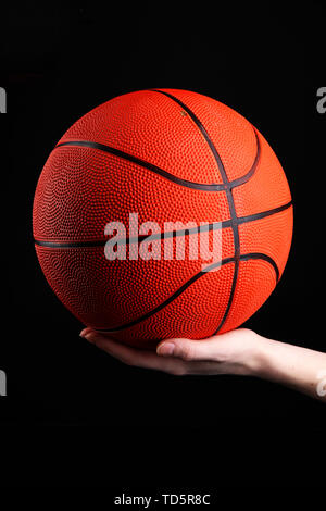 En basket-ball femme Main sur fond noir Banque D'Images