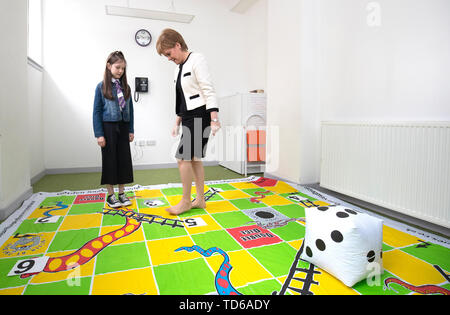 Premier ministre Nicola Sturgeon joue un 'snakes et échelles' jeu avec Ava Dewar, 9, au cours d'une visite au centre de soins de Dundee en Ecosse. Banque D'Images
