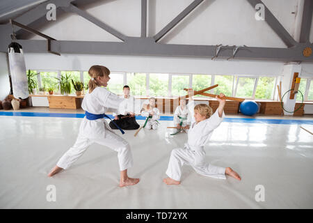 Attaquer avec jo. Girl wearing kimono blanc garçon attaque avec jo alors que l'aikido d'apprentissage Banque D'Images