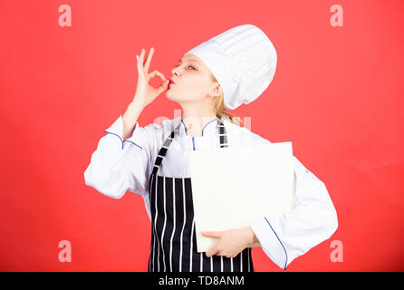 Happy woman cooking alimentation saine par recette. menu du restaurant. Suivre un régime culinaire. Femme au chapeau et un tablier cook. chef professionnel en cuisine. Cuisine. Femme au foyer avec livre de cuisine. Les choix alimentaires. Banque D'Images