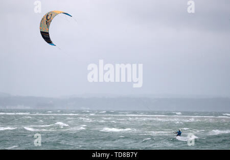 Un kite surfer prend avantage des forts vents au large de la plage de l'Ouest sur Hayling Island dans le Hampshire. Banque D'Images