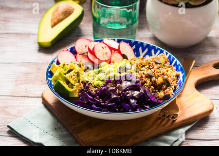 Bol Bouddha avec des couleurs arc-en-ciel - avocat ingrédients fermentés, du chou rouge, quinoa, radis, haricots verts, le sésame et les graines de citrouille. Servie sur wo Banque D'Images