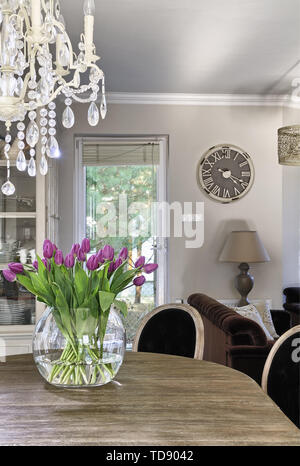 Tulipe rose en grand vase de verre transparent sur la table à manger en bois dans la salle à manger spacieuse de l'homme britannique et irlandais seulement Banque D'Images