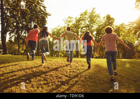 Un groupe de jeunes gens heureux tournant au coucher du soleil sur la nature. Les amis le soir dans le parc. Banque D'Images