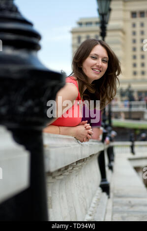 Élégante belle jeune femme en jolie robe posant sur le balcon. Portrait de femme tendre attrayante en robe de printemps regardant loin et souriant pendant que sta Banque D'Images