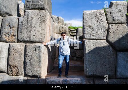 Homme posant devant l'énorme rochers de Sacsayhuaman à Cusco - Pérou. Banque D'Images