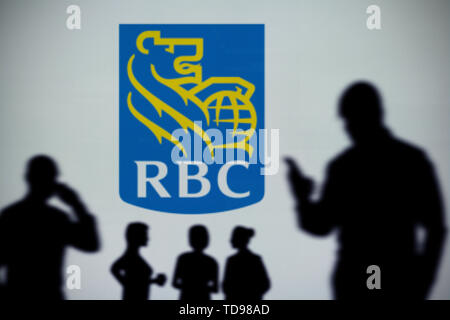 Le logo de RBC Banque Royale est vu sur un écran LED à l'arrière-plan tandis qu'une silhouette personne utilise un smartphone (usage éditorial uniquement) Banque D'Images