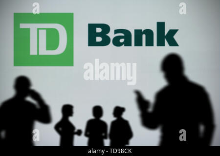 Le logo de la Banque TD est vu sur un écran LED à l'arrière-plan tandis qu'une personne utilise la silhouette d'un smartphone dans l'avant-plan (usage éditorial uniquement) Banque D'Images