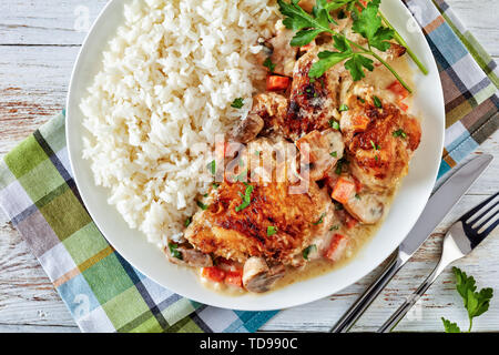 Vue de dessus de la fricassée de poulet sur une plaque avec de la viande de poulet - riz doré et mijotée dans du vin blanc, sauce crème aux champignons et légumes, cla Banque D'Images