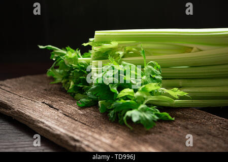 Bouquet de céleri frais sur table en bois avec des feuilles sur fond noir. Produits et ingrédients de légumes sains. Fraîcheur et à base de plantes faible calo Banque D'Images