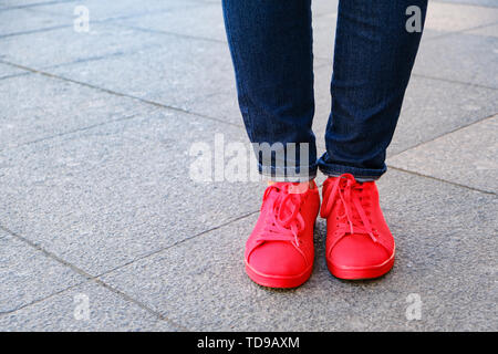 Jour avec . Pieds de la jeune fille dans les chaussures. Espadrilles rouge et jeans. En attente d'une date Banque D'Images