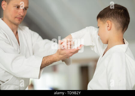 Bel homme. Handsome man wearing kimono blanc petit garçon enseignement mouvements d'aikido Banque D'Images