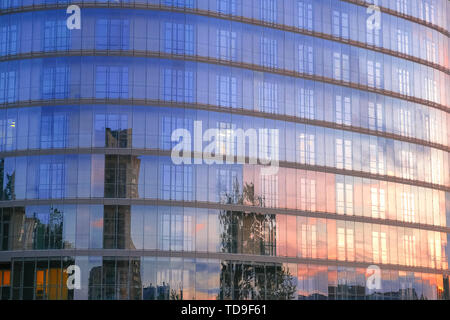 Bâtiment moderne de plusieurs étages avec une façade en verre. La soirée sunset sky se reflète dans les fenêtres de la façade Banque D'Images
