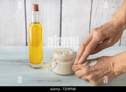 La main de l'épandage fissurée. crème argan Crème pour les mains argan fissuré dans un bocal en verre. Bouteille d'huile d'argan Banque D'Images