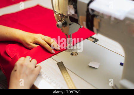 Une femme coud dans une usine de vêtements. un tailleur-surfaces avec une machine à coudre sur une bonneterie. Banque D'Images