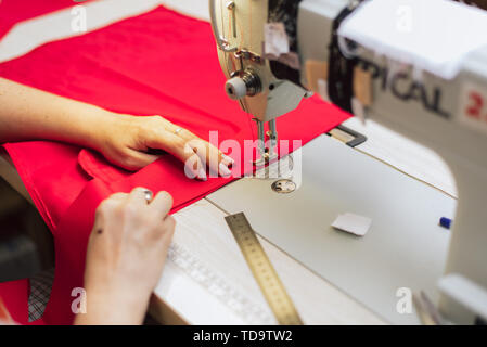 Une femme coud dans une usine de vêtements. un tailleur-surfaces avec une machine à coudre sur une bonneterie. Banque D'Images