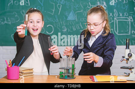 Attention l'exécution de la réaction chimique. Connaissances de base en chimie. Les filles étudient la chimie. Faire en chimie intéressant. Expérience Pédagogique concept. Microscope et de tubes à essai sur table. Banque D'Images