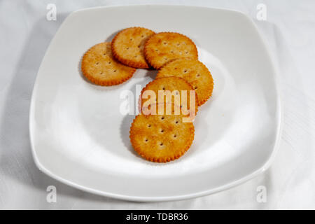 Craquelins au fromage rond avec des raisins sur une place blanche Banque D'Images