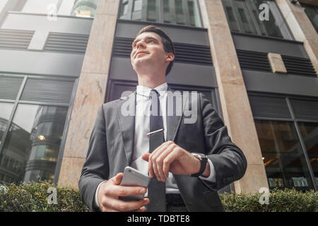 Close up of businessman à côté de l'édifice, catégorie gratte-ciel au centre-ville en attente d'une réunion. Vue de dessous. Banque D'Images