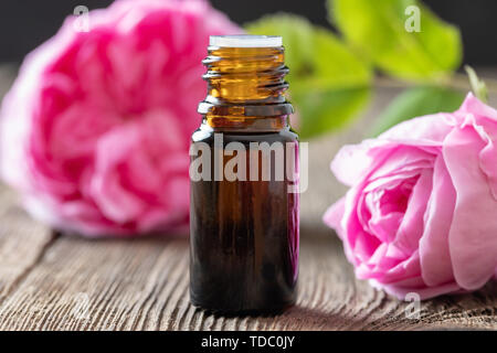 Une bouteille d'huile essentielle avec des fleurs rose de mai Banque D'Images