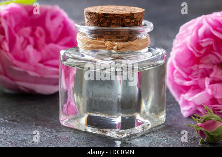 Une bouteille d'huile essentielle avec des fleurs rose de mai Banque D'Images