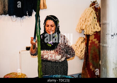 Göreme, Turquie - 14 juin 2019 : les femmes d'Artisan de la préparation des fils de soie d'une manière traditionnelle à coudre des vêtements. Banque D'Images