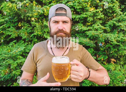 Boire comme un hipster. Buveur Hipster holding beer mug. Hipster barbu aime boire la bière sur la nature. Homme Hipster avec craft beer. Boire seulement le meilleur et le plus coûteux de la bière. Banque D'Images