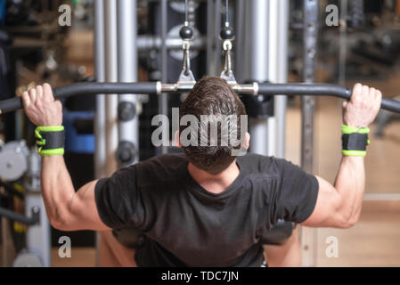 Formation l'homme en prenant les muscles dorsaux et les poignées vers le bas. L'exercice de force concept . Banque D'Images