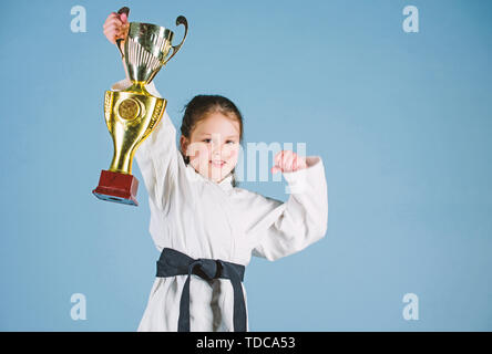 Le succès dans le sport de combat unique. pratiquer le Kung Fu. enfance heureuse. winner petite fille dans gi sportswear. Petite fille avec champion cup. arts martiaux et de l'énergie Activité pour les enfants. Trouver le poser. Banque D'Images