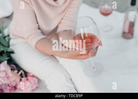 Verre de vin rose in woman's hand on pique-nique. Rognées. Banque D'Images