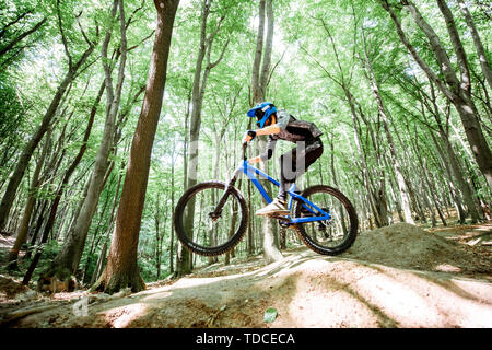 Cycliste professionnel bien équipé à cheval sur la piste en forêt avec des toboggans pour le saut. Concept d'un sport extrême et enduro à vélo. Image avec moti Banque D'Images