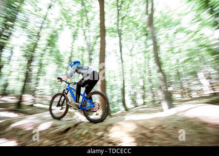 Cycliste professionnel bien équipé à cheval sur la piste en forêt avec des toboggans pour le saut. Concept d'un sport extrême et enduro à vélo. Image avec moti Banque D'Images