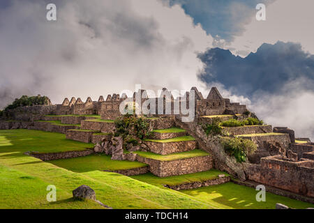 Vue mystique sur le Machu Picchu ville ruines couvertes de brouillard avec les rayons du soleil en passant par les nuages. Ville sacrée de l'Inca pendant le lever du soleil. Banque D'Images