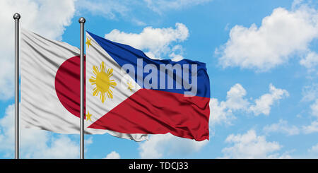 Le Japon et les Philippines drapeaux dans le vent contre ciel bleu nuageux blanc ensemble. Concept de diplomatie, de relations internationales. Banque D'Images