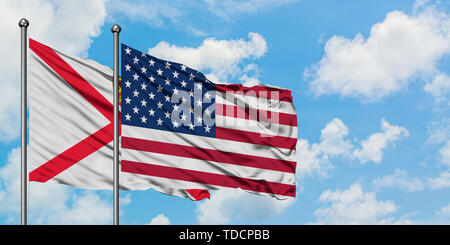 Jersey et de brandir le drapeau des États-Unis dans le vent contre ciel bleu nuageux blanc ensemble. Concept de diplomatie, de relations internationales. Banque D'Images