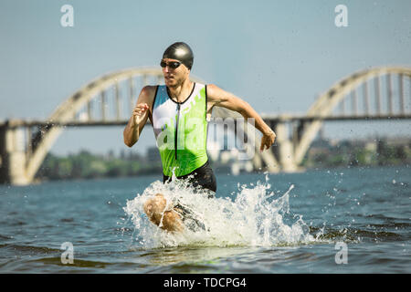 Triathlète professionnel swimming in river's l'eau libre. Homme portant un équipement de natation triathlon pratique sur la plage en été. Concept de bonne hygiène de vie, sport, d'action, de mouvement et de mouvement. Banque D'Images