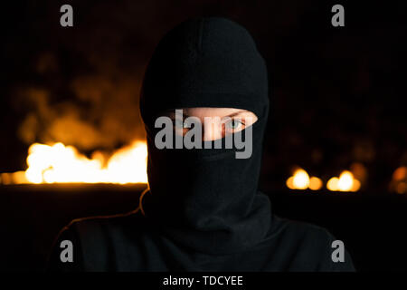 Portrait de femme militante qui protestaient à balaclava près de barricades dans la nuit Banque D'Images