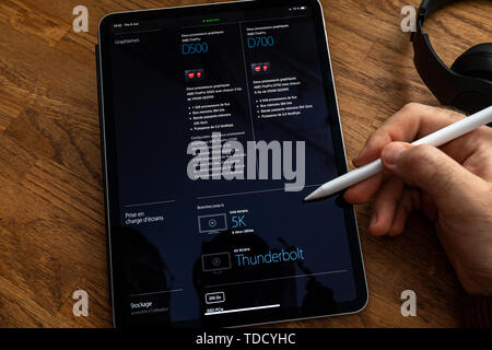 Paris, France - Nov 6, 2019 : lecture sur tablette iPad Apple Pro sur station de travail professionnelle puissant ordinateur Mac Pro avec comparer table avec les spécifications techniques entre les machines GPU Banque D'Images