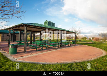 De pique-nique couverte sur un parc pittoresque sous ciel nuageux ciel bleu. Une montagne couverte de neige et résidentiel peut être vu dans la distance. Banque D'Images