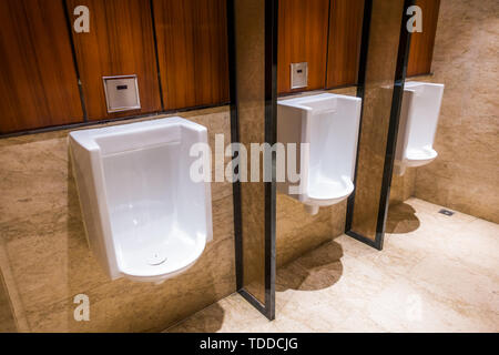 Une rangée de rinçage automatique d'urinoirs dans les toilettes publiques. Banque D'Images