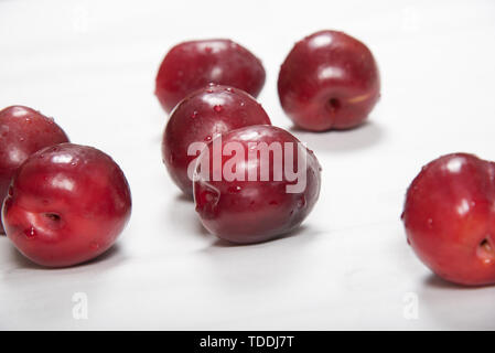 Prune rouge posé nonchalamment sur fond blanc Banque D'Images